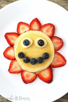 a pancake with strawberries and blueberries on it is decorated to look like a face