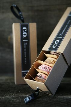 three donuts in a box sitting next to each other on a wooden table with black ribbon