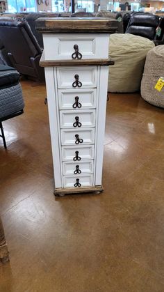 a white cabinet sitting on top of a hard wood floor in a room filled with furniture