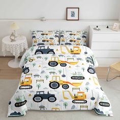 a bed covered in a white comforter with yellow and black construction vehicles on it