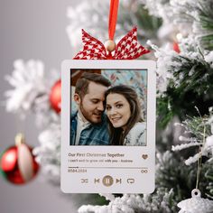 an ornament hanging from a christmas tree with a couple's photo on it