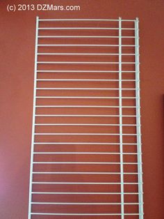 a white wire shelf sitting on top of a red wall