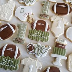 decorated cookies with footballs, shirts and numbers are arranged on a white tablecloth