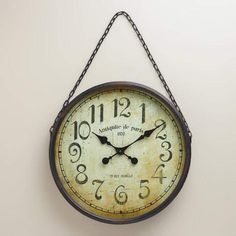 a clock hanging from the side of a wall with numbers on it's face