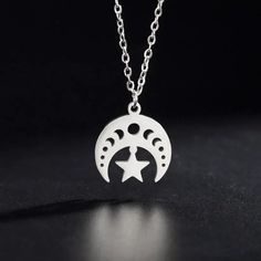 the moon and star necklace is shown on a black surface