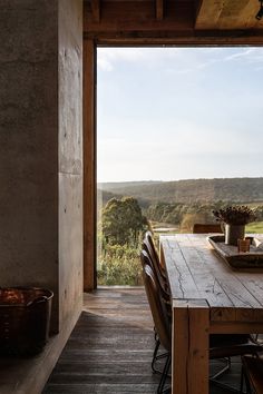 a wooden table sitting on top of a wooden floor next to a tall building with an open door