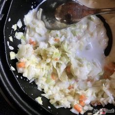 a bowl filled with coleslaw and carrots next to a spoon in it