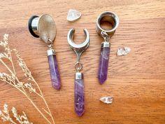 three pieces of jewelry sitting on top of a wooden table next to flowers and scissors