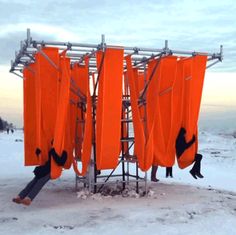 two people are hanging out in the snow with orange surfboards attached to a pole