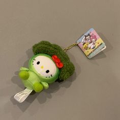 a green stuffed animal with a red bow on it's head is attached to a key chain