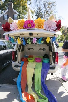 the trunk of a car decorated with paper flowers and unicorn ears on it's roof