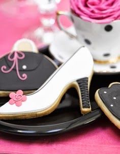 decorated cookies are sitting on a plate next to a cup and saucer with pink roses