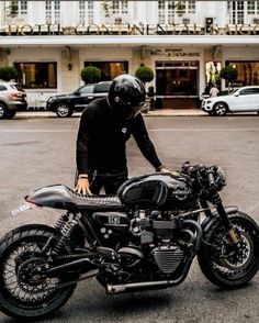 a man in black riding on the back of a motorcycle