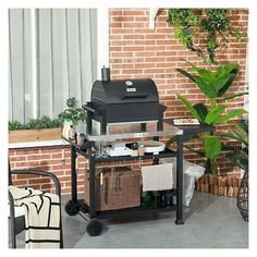 a bbq grill sitting on top of a table next to a potted plant