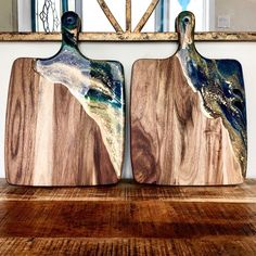 two wooden cutting boards sitting next to each other on a wood floor in front of a mirror