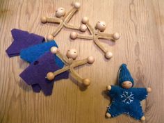 three wooden peg dolls sitting next to each other on top of a wood table covered in snowflakes