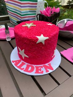 a red cake sitting on top of a table covered in pink and white frosting