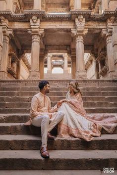 two people sitting on some steps in front of an old building