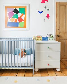 a baby's room with a crib, dresser and painting on the wall