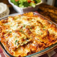 a casserole dish with meat, cheese and vegetables in it on a checkered table cloth