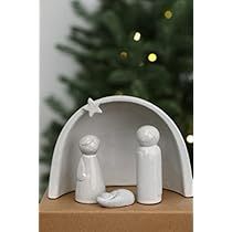 two white figurines sitting on top of a cardboard box next to a christmas tree