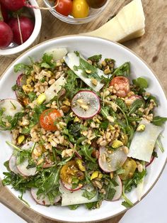 a salad with radishes and other vegetables on a plate next to some cheese