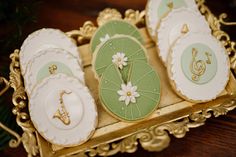 decorated cookies in the shape of umbrellas and flowers on a gold tray with greenery