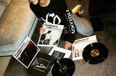 a woman sitting on the floor with some records and cds