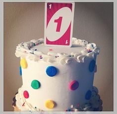 a birthday cake decorated with white frosting and colorful sprinkles, topped with a one candle