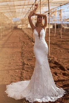 a woman in a white wedding dress posing for the camera with her hand on her head