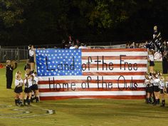 a group of cheerleaders standing in front of an american flag with the words land of the free home of the owls written on it