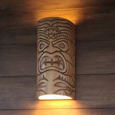 a light that is on the side of a wooden wall with a tiki face