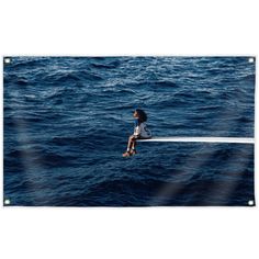 a woman sitting on top of a boat in the middle of the ocean with her back to the camera