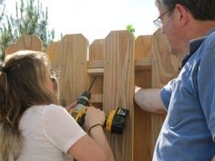 a man and woman are working on a wooden fence with drillers in their hands