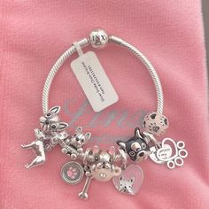 the charm bracelet has many charms on it and is attached to a pink t - shirt