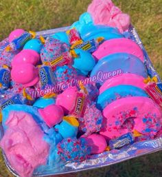 a person holding up a box filled with pink and blue play doughnuts on top of green grass