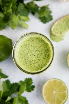 a green smoothie in a glass surrounded by limes and cilantro