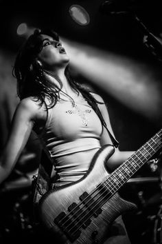 a woman holding a guitar while standing in front of a microphone