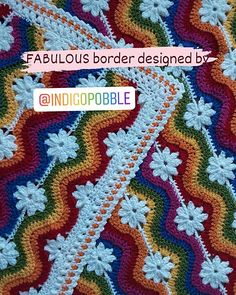 a colorful crocheted blanket with white flowers on the bottom and rainbows in the middle