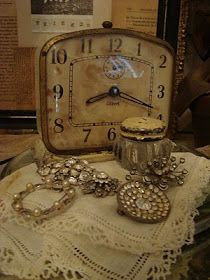 an antique clock and some jewelry on a table