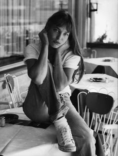 a woman sitting on top of a table next to chairs