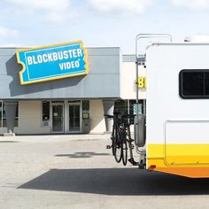 a yellow and white trailer parked in front of a building with bicycles on the rack