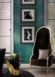 a living room with green walls and pictures on the wall, two chairs in front of a coffee table