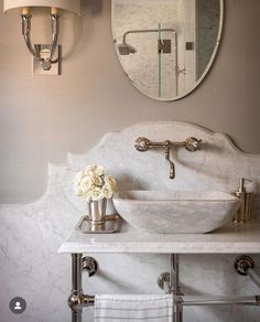 a white sink sitting under a bathroom mirror next to a wall mounted faucet