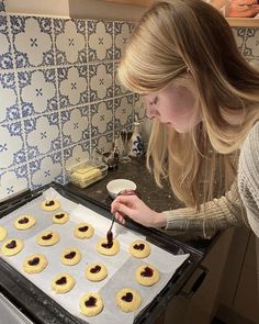 a woman is making cookies in the kitchen