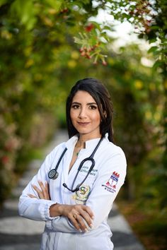 a woman with a stethoscope standing in front of some bushes and trees