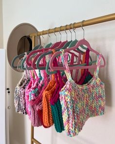 there are many knitted sweaters hanging on the clothes rack in front of the door