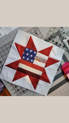 a red white and blue star quilted on top of a piece of fabric next to scissors