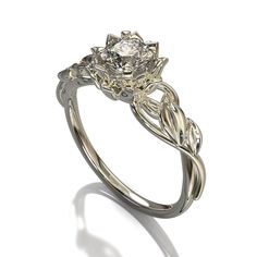 a white gold ring with an intricate design on the band and center stone surrounded by leaves