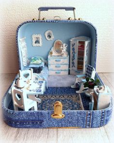 a dollhouse in a suitcase with furniture inside and blue carpet on the floor below